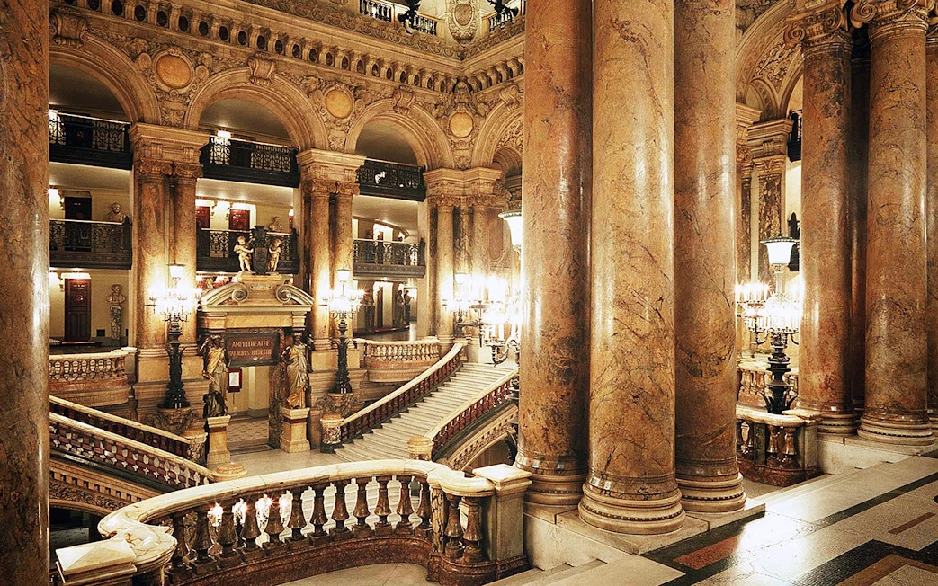 Grand staircase and ornate columns inside Opera Garnier, Paris.