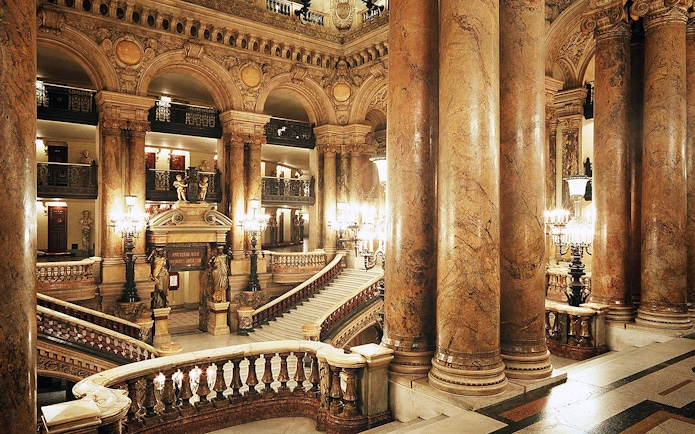Grand staircase and ornate columns inside Opera Garnier, Paris.