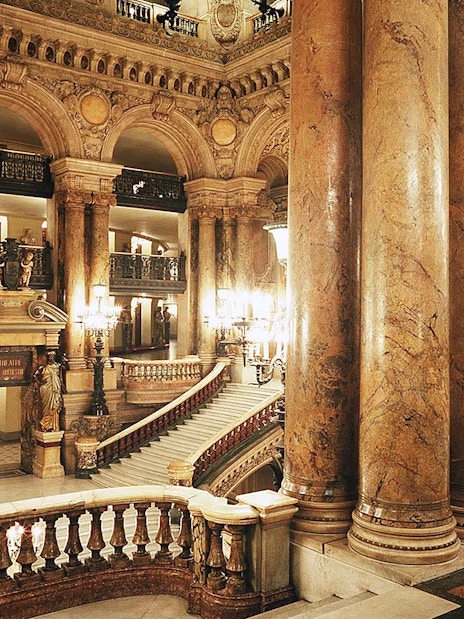 Grand staircase and ornate columns inside Opera Garnier, Paris.