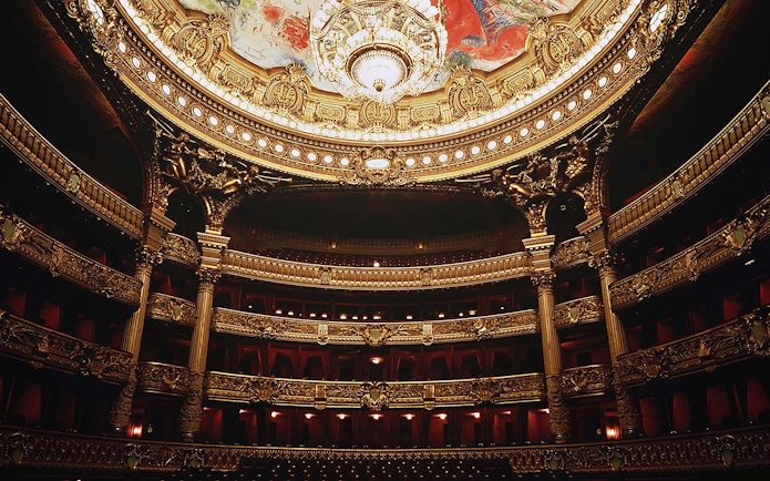Ornate interior of Opera Garnier in Paris with grand chandelier and detailed balconies.