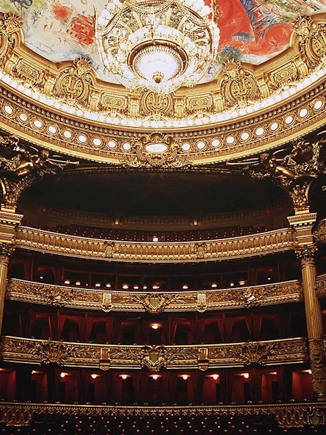 Ornate interior of Opera Garnier in Paris with grand chandelier and detailed balconies.