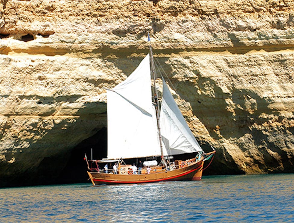 Tourists enjoying a sunny Algarve cruising experience on a speedboat with the view of stunning cliffs and clear blue waters