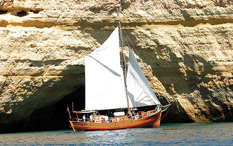 Tourists enjoying a sunny Algarve cruising experience on a speedboat with the view of stunning cliffs and clear blue waters