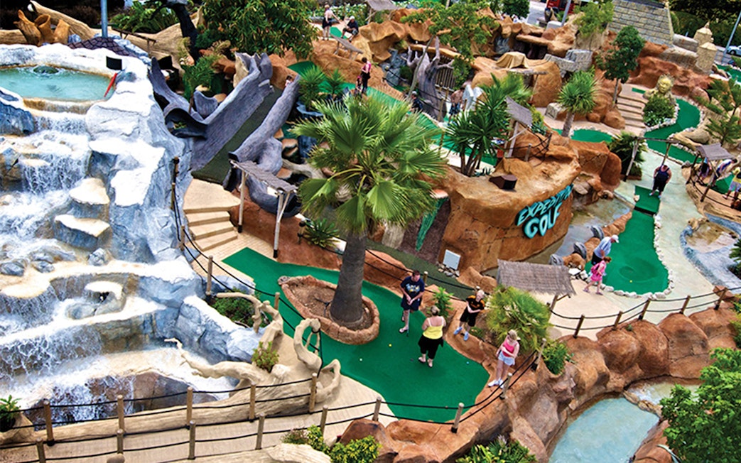Mini-golf course at Katmandu Park with waterfalls and tropical landscaping.