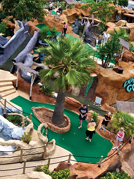 Mini-golf course at Katmandu Park with waterfalls and tropical landscaping.