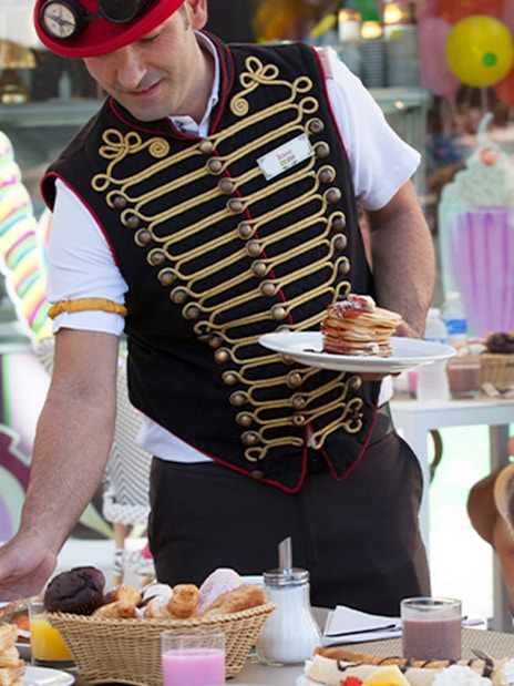 Server in themed attire serving food to a family at Katmandu Park.