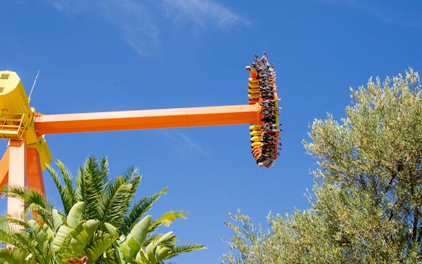 Roller coaster ride at Terra Mitica theme park against blue sky.