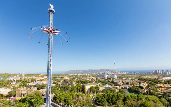 Terra Mitica theme park with tall swing ride and scenic view of Benidorm, Spain.