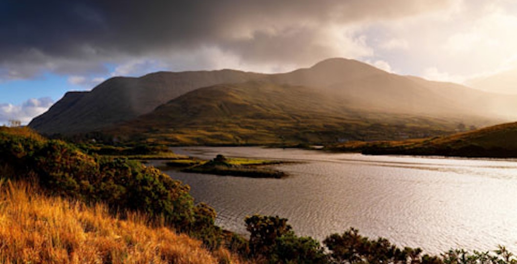 Connemara landscape with mountains and lake under dramatic sky.