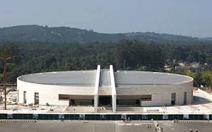 Fatima pilgrimage site with modern basilica, surrounded by forest, part of Algarve tour.