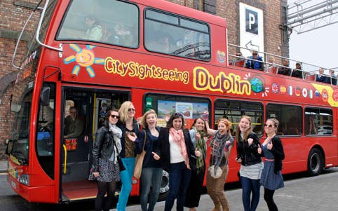 Red double-decker bus for City Sightseeing Dublin with tourists ready to explore.