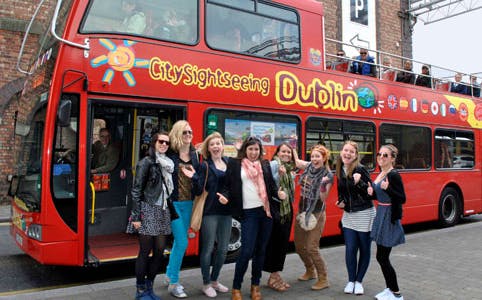 Red double-decker bus for City Sightseeing Dublin with tourists ready to explore.
