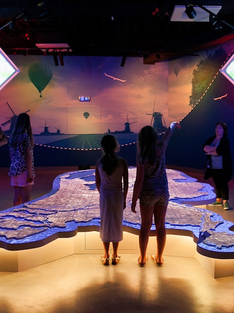 Visitors exploring interactive map at This is Holland exhibit in Amsterdam.