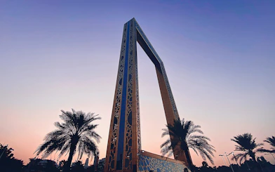 Dubai Frame at sunset with palm trees in the foreground.