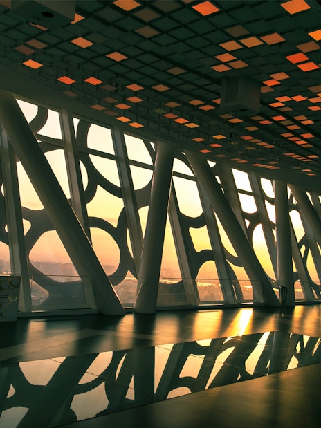 Interior view of Dubai Frame with cityscape at sunset through geometric windows.