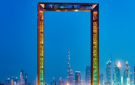 Dubai Frame with city skyline at night, highlighting IMG Worlds of Adventure tour.