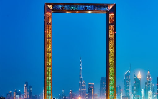 Dubai Frame with city skyline at night, highlighting IMG Worlds of Adventure tour.