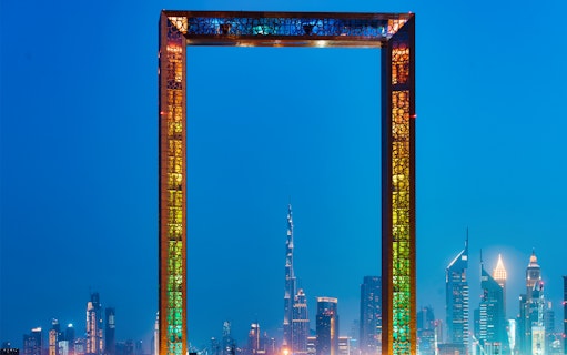 Dubai Frame with city skyline at night, highlighting IMG Worlds of Adventure tour.