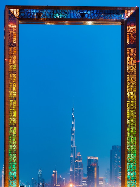 Dubai Frame with city skyline at night, highlighting IMG Worlds of Adventure tour.