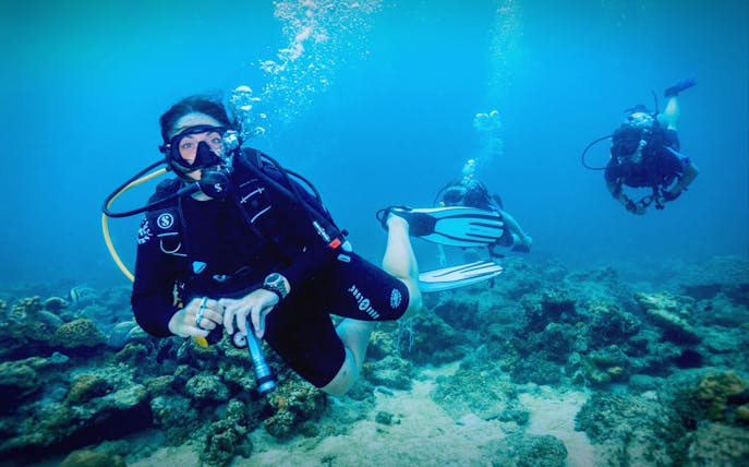 Scuba divers exploring coral reef at Dubai Aquarium.