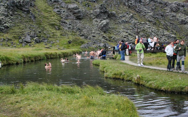 Visitors enjoying the Secret Lagoon Bath in a natural setting.