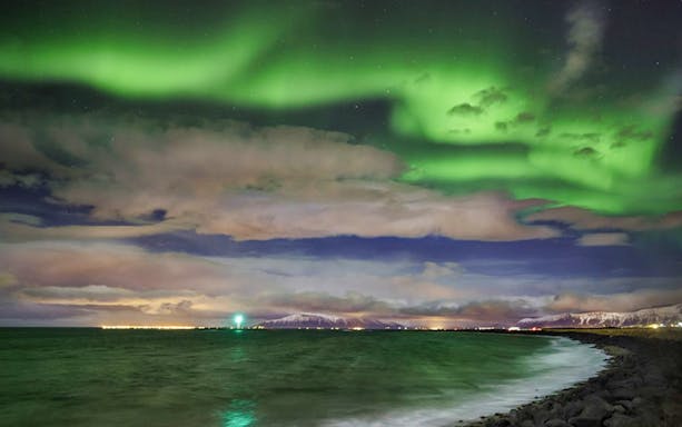 Northern Lights over ocean near Secret Lagoon, Iceland.