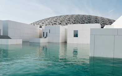 Louvre Abu Dhabi exterior with water reflection and dome structure.