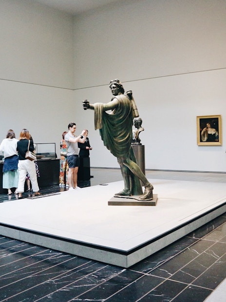 Visitors viewing sculptures and paintings at Louvre Abu Dhabi.