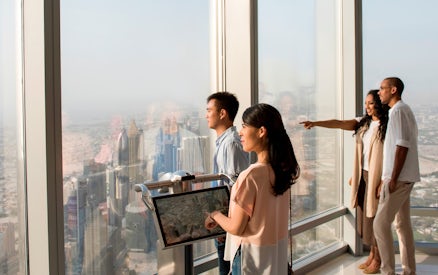 Visitors enjoying the view from Burj Khalifa observation deck, overlooking Dubai skyline.