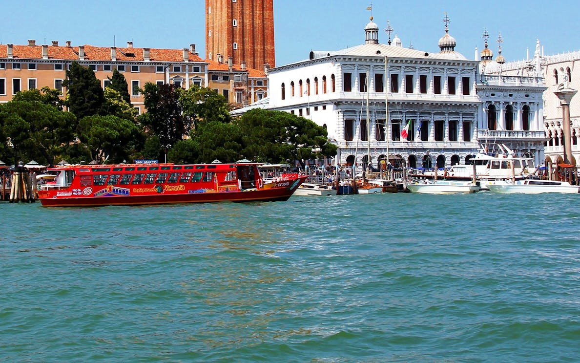 Venice hop-on hop-off boat near historic buildings on the Grand Canal.