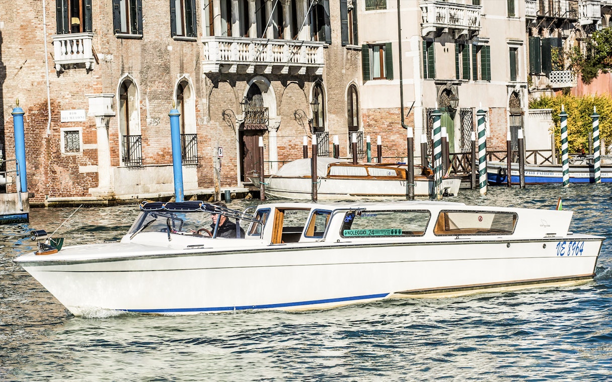 Water taxi navigating Venice canal near historic buildings.