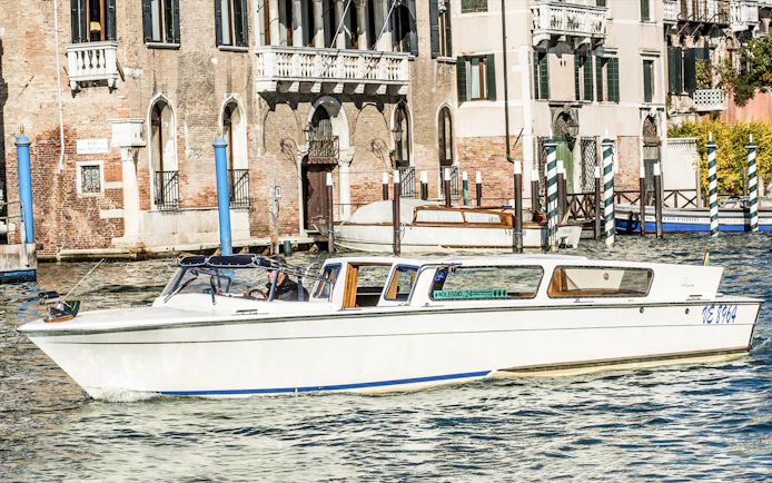 Water taxi navigating Venice canal near historic buildings.