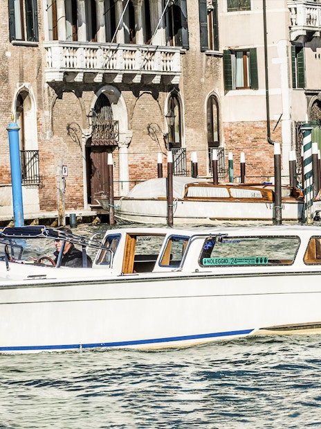 Water taxi navigating Venice canal near historic buildings.