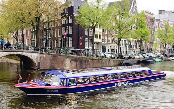 City canal cruise boat passing traditional Amsterdam houses.