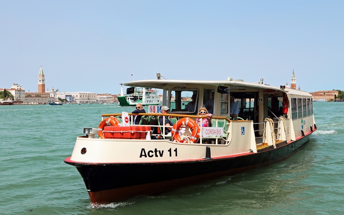Venice ACTV water bus on Grand Canal with St. Mark's Campanile in background.