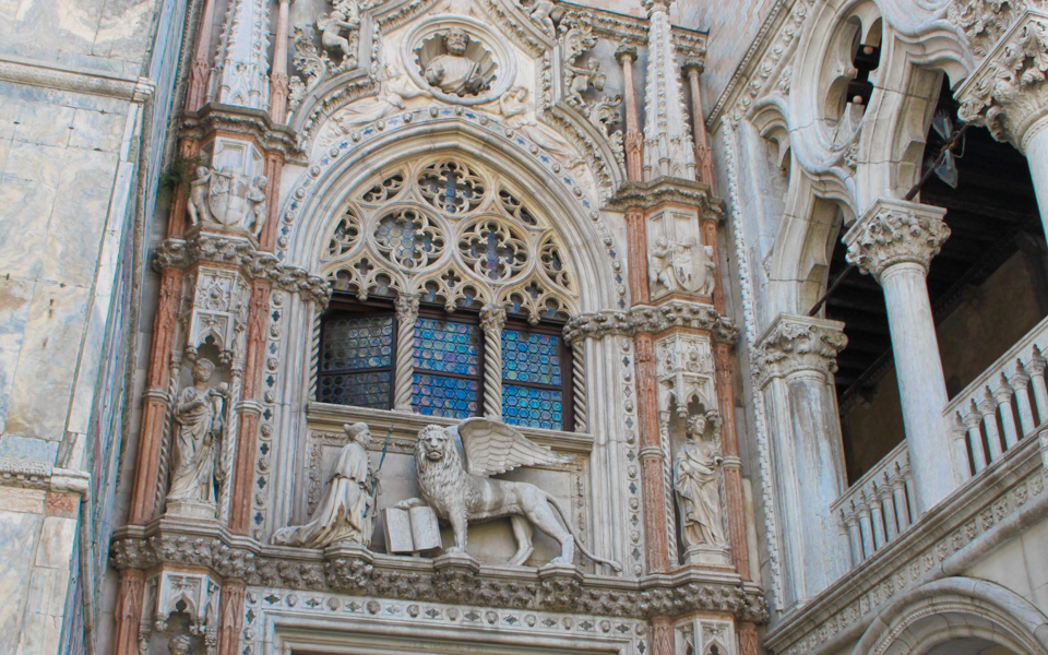 Facade of Doge’s Palace in Venice with ornate sculptures and stained glass windows.