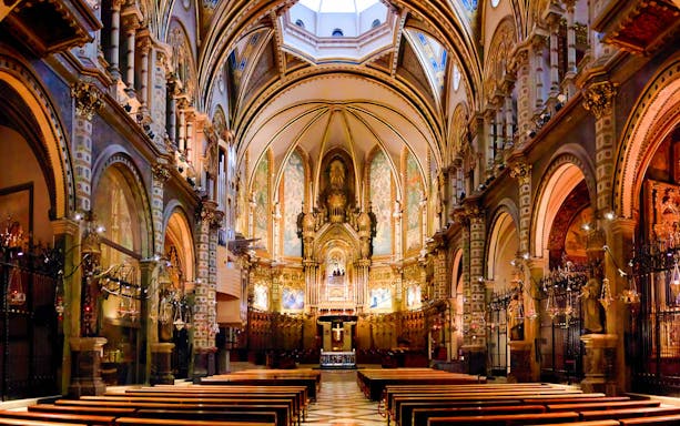 Interior of Montserrat Monastery Basilica, Barcelona, featuring ornate arches and altar.