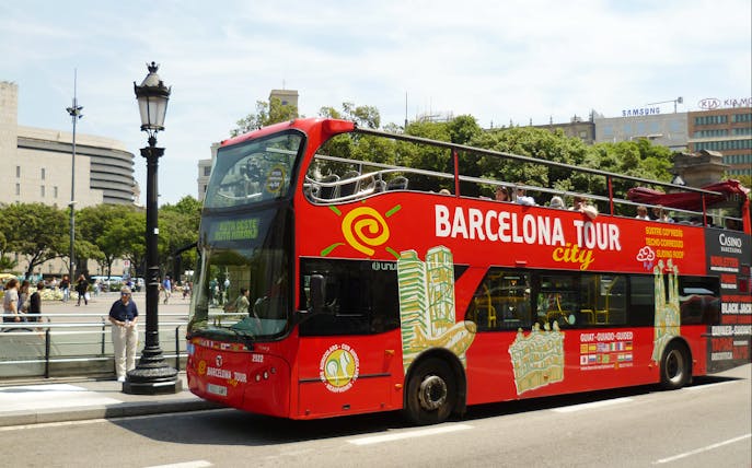 Barcelona hop-on hop-off tour bus near city landmarks.