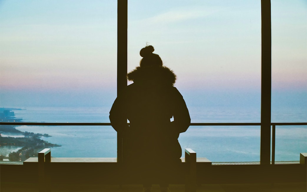 Person viewing Lake Michigan from 360 Chicago observation deck.