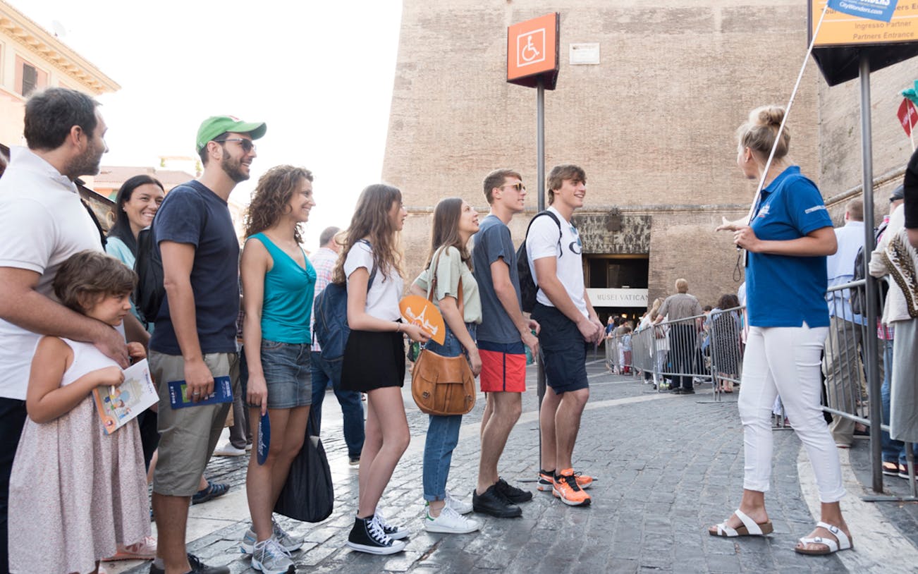 Tourists in line for Vatican Museum entrance with guide, Rome.