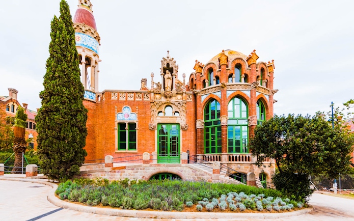 Sant Pau Modernista's ornate red brick facade with green windows in Barcelona.