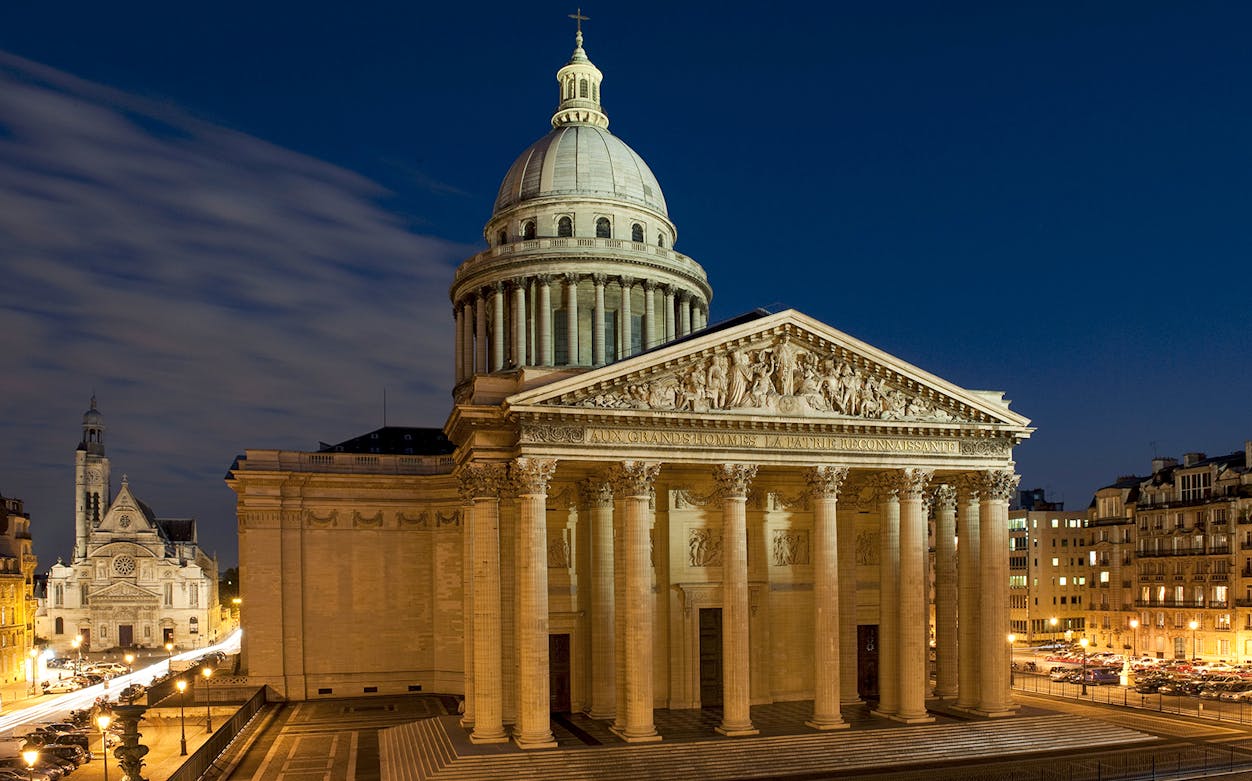 Pantheon in Paris illuminated at night, showcasing neoclassical architecture.