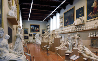 Sculpture gallery at Academia Gallery, Florence, featuring classical statues and busts.