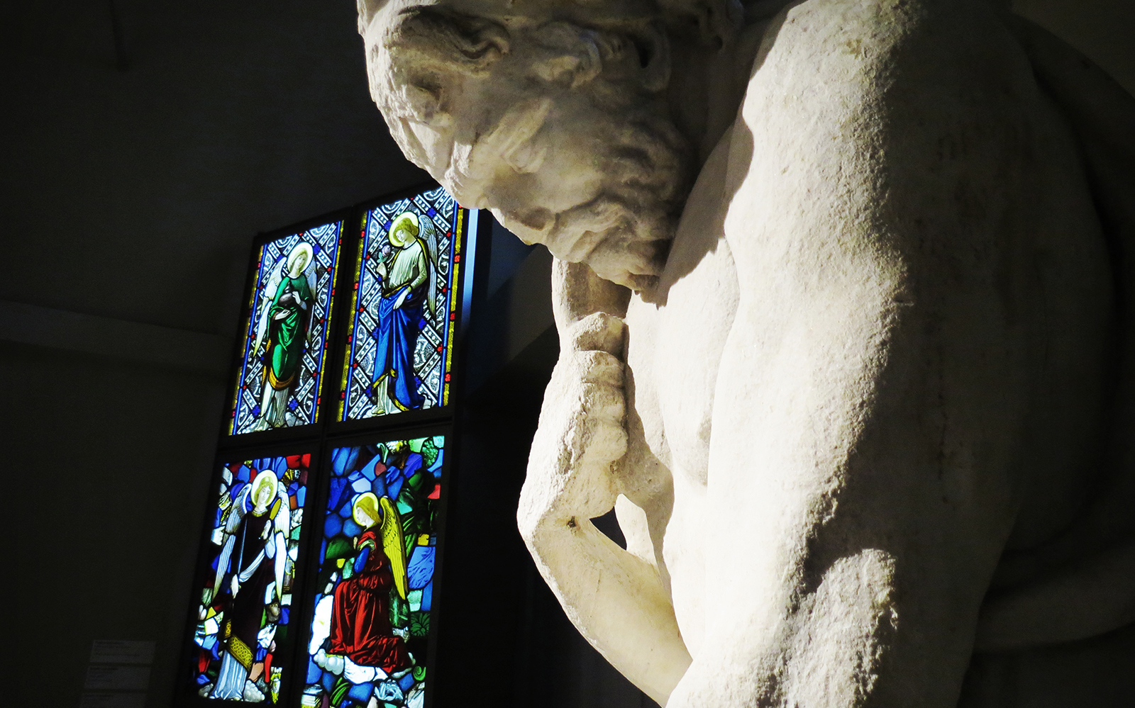 Statue and stained glass inside Duomo Cathedral Museum, Milan.
