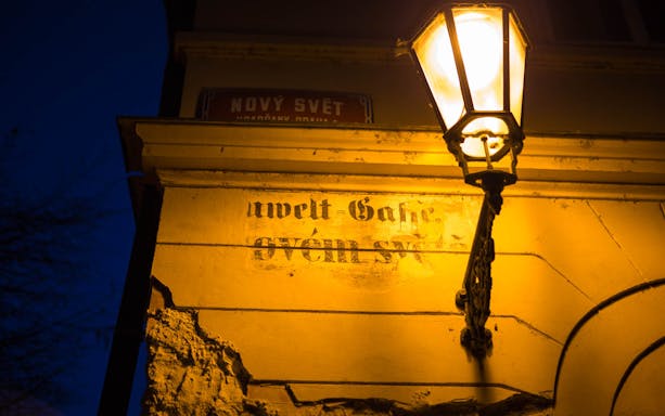 Street lamp illuminating a wall with faded text in Nový Svět, Prague.