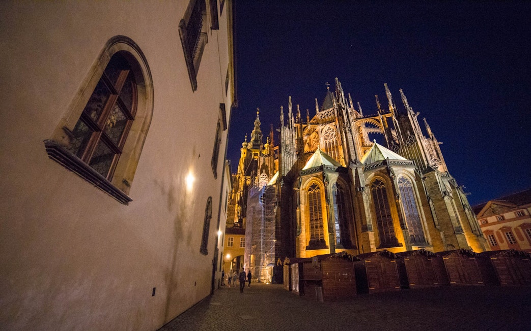 Prague Castle at night with illuminated Gothic architecture.