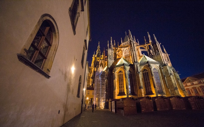 Prague Castle at night with illuminated Gothic architecture.