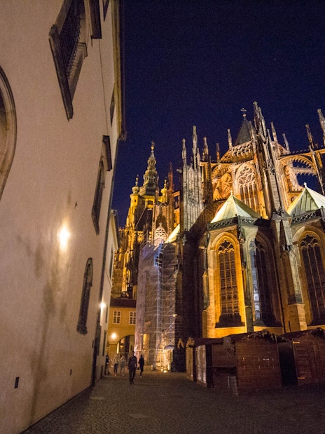 Prague Castle at night with illuminated Gothic architecture.