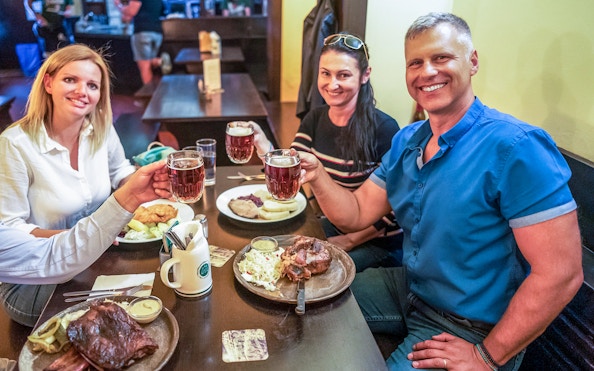 Group enjoying traditional Czech meal and beer during Prague city tour lunch cruise.