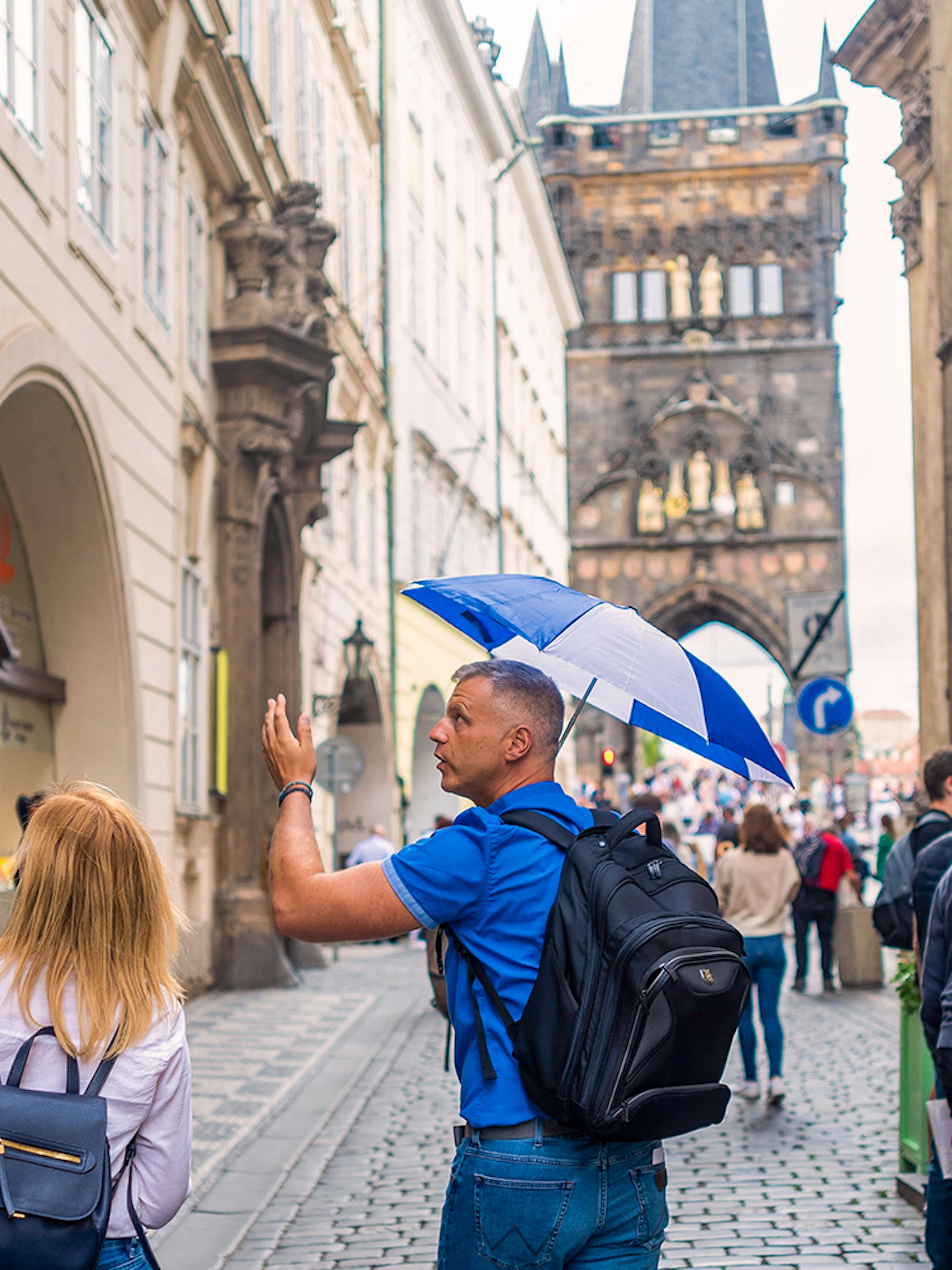 Tour guide leading group near Charles Bridge in Prague.